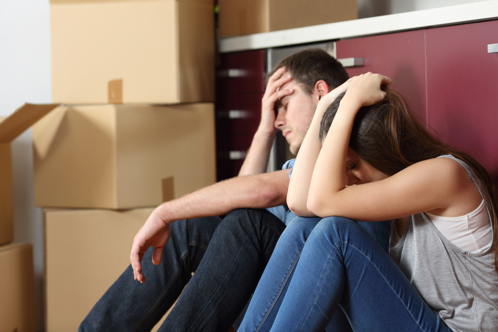 Angry evicted couple worried about moving houses while sitting on the floor in the kitchen