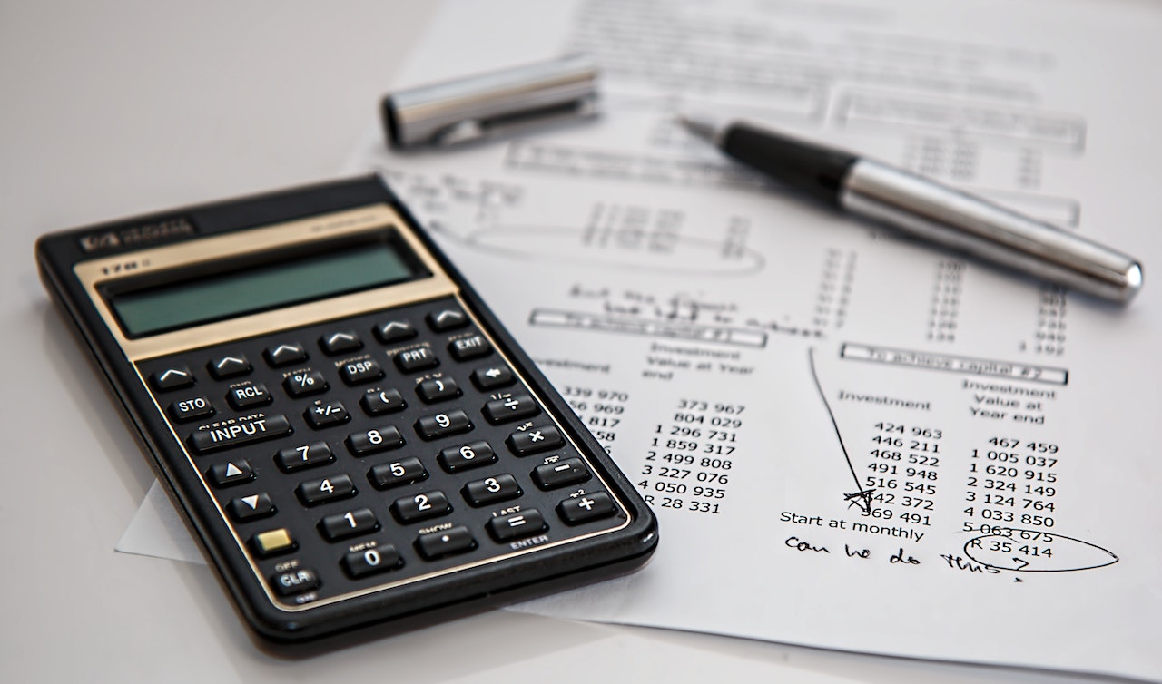 calculator and a ballpen on top of budget list
